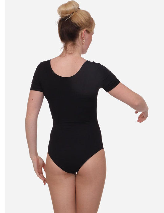 Rear view of a woman in an elegant black leotard for dance with her hair in a bun, demonstrating a ballet arm position.