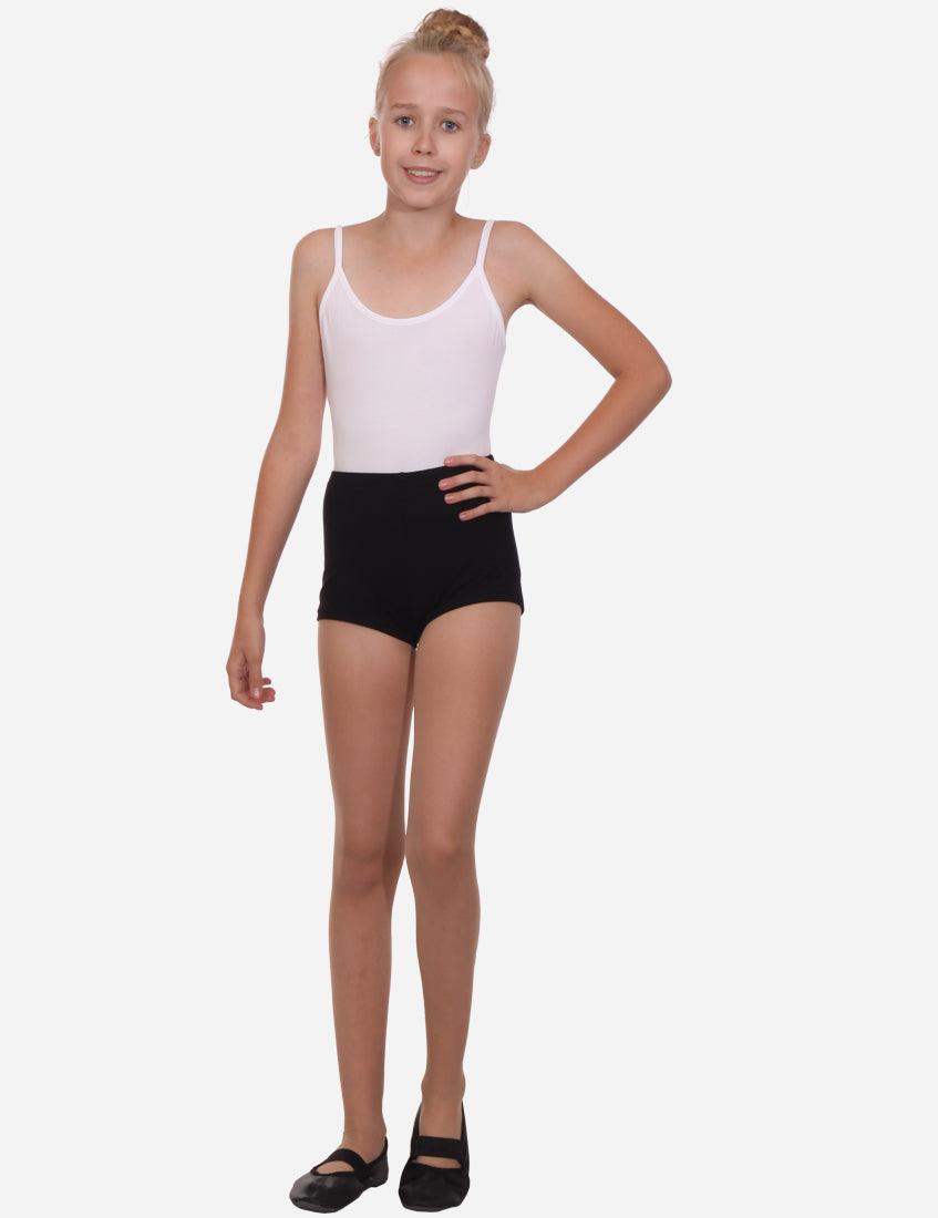 Side profile of a young girl in black elastic shorts paired with a white tank top and ballet flats, poised against a plain background.