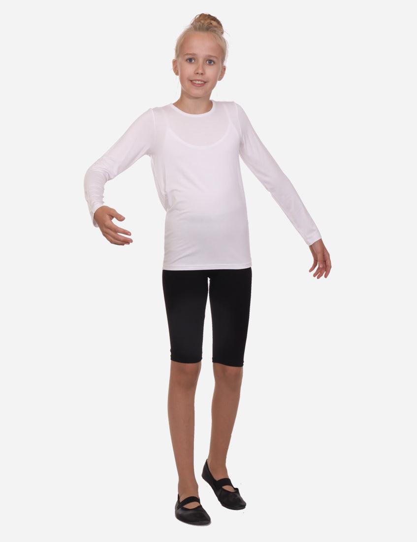 Young girl in a white long sleeve shirt and black capri leggings standing with arms outstretched on white background
