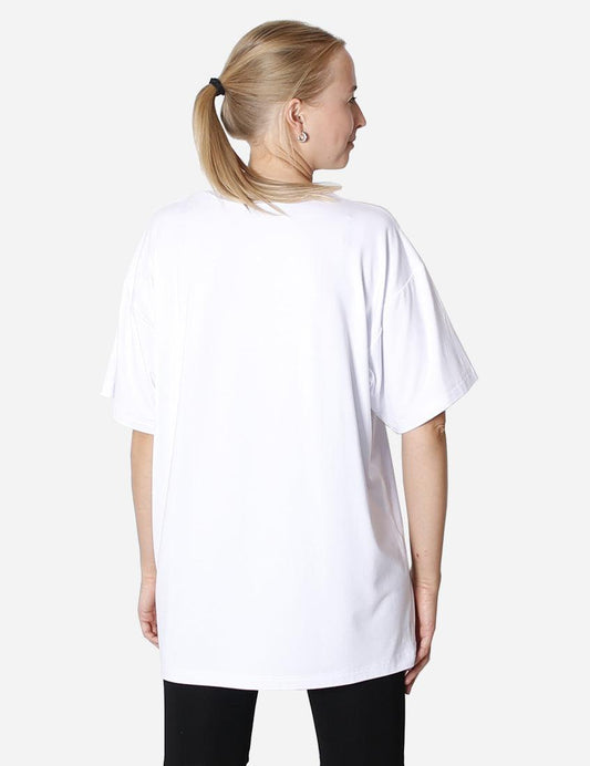 Woman from behind wearing oversized white unisex t-shirt on a plain background.