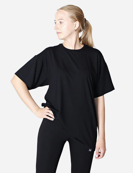 Side view of a woman wearing a black oversized unisex t-shirt on white background