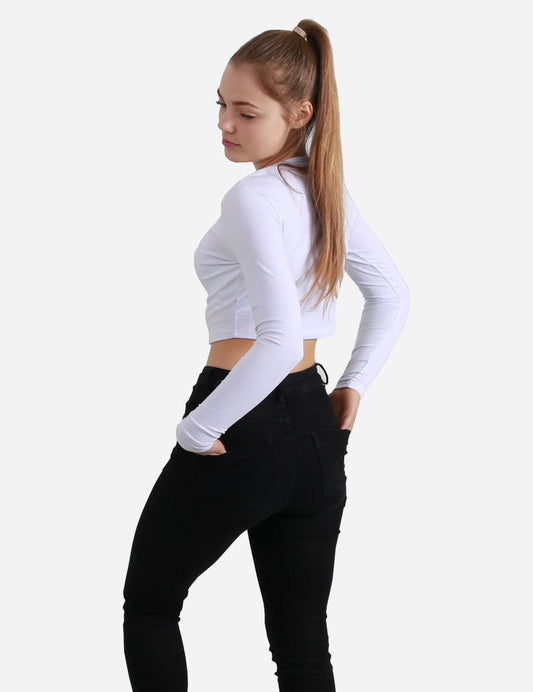 Side view of a woman in a white cropped long sleeve top looking away on white background