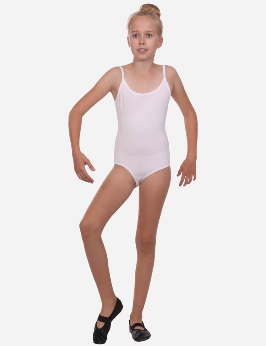 Child dancer in a white leotard with straps, ready to dance with black ballet shoes, against a light background.