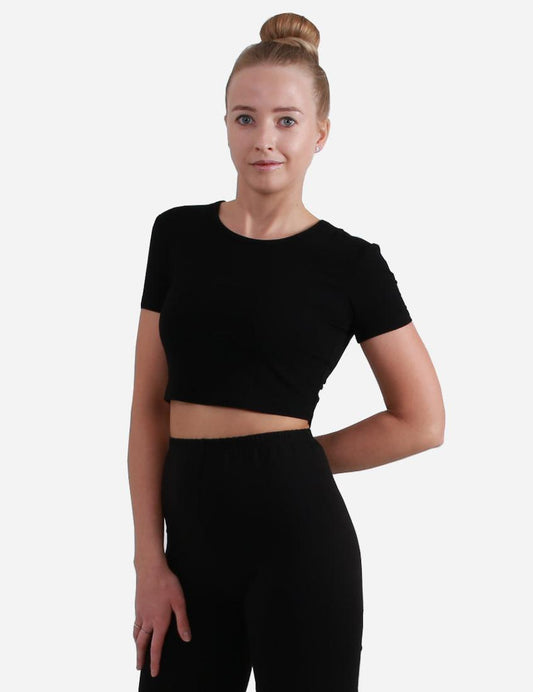Woman in black short sleeve cropped top facing forward on white background