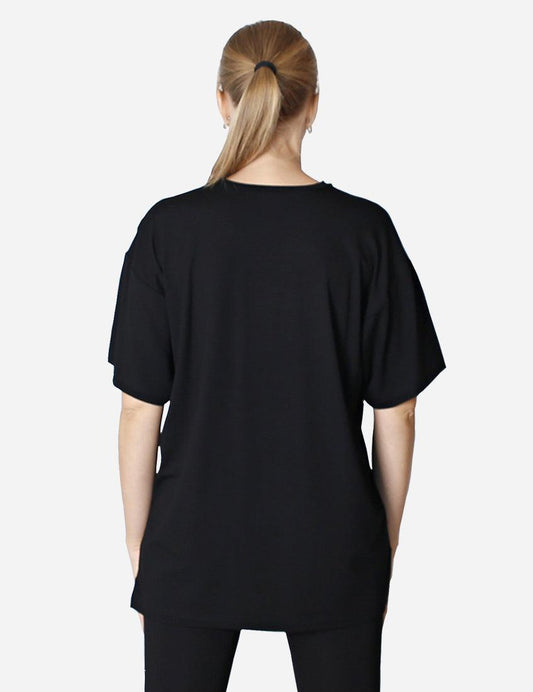 Woman in an oversized black t-shirt and black shorts standing on white background