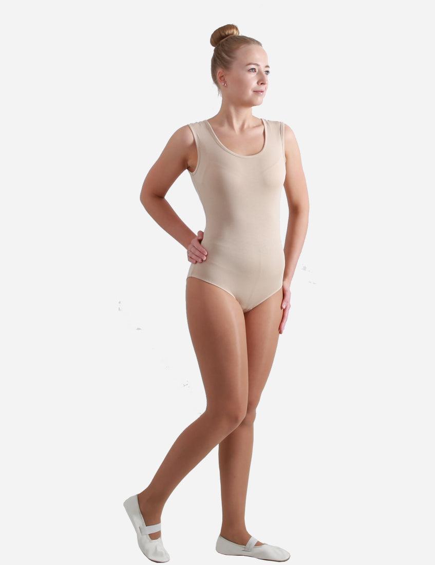 Adult female ballet dancer in a sleeveless nude leotard standing in a poised position against a white background.