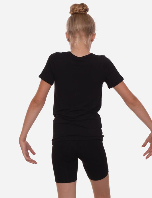 Back view of a young girl in a black short-sleeved t-shirt and shorts, standing isolated on a white background