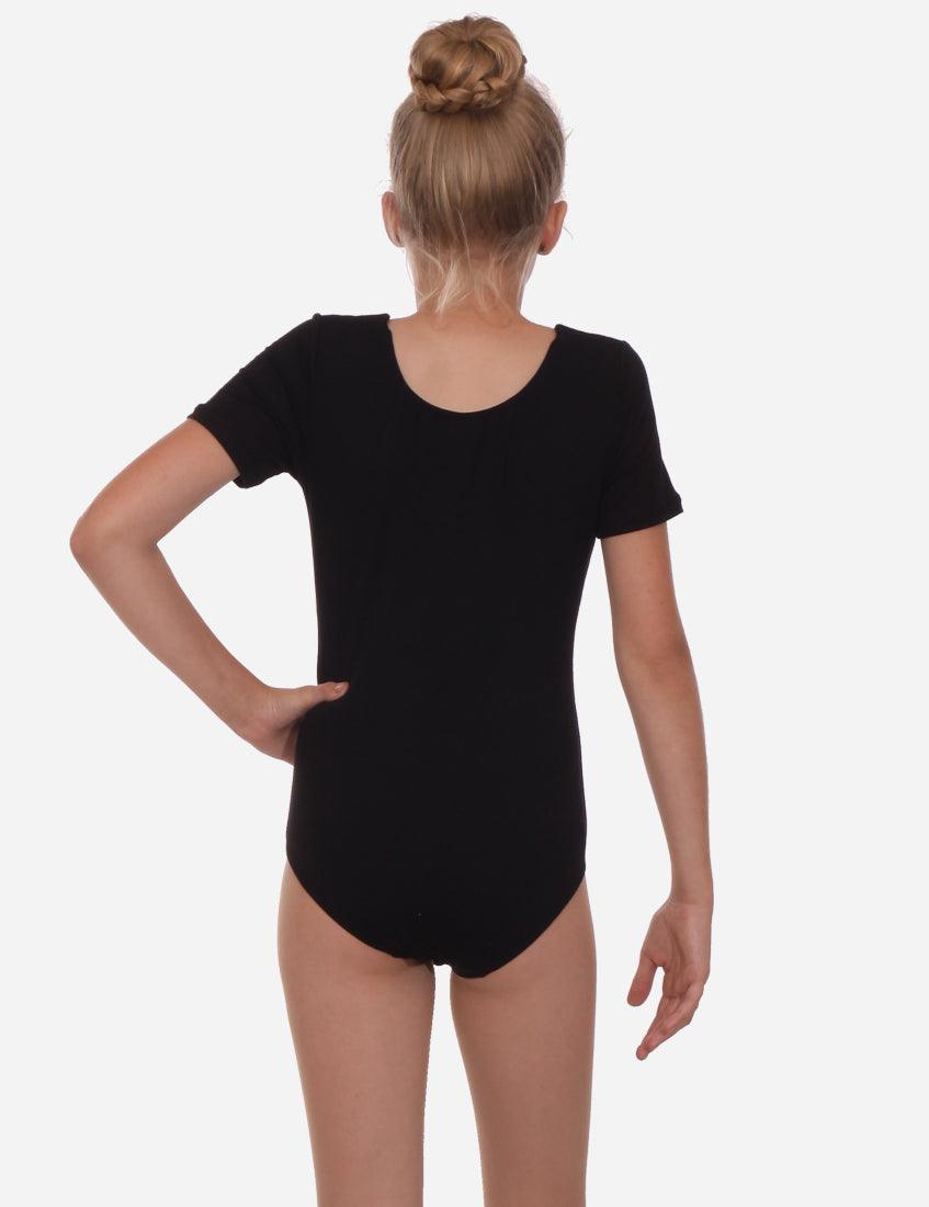 Back view of a child wearing a black short sleeve leotard, with a hair bun, preparing for a dance performance.