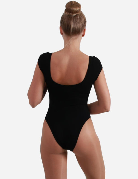 ack view of a woman wearing a black leotard with winged sleeves, showcasing the scoop back design with a bun hairstyle.