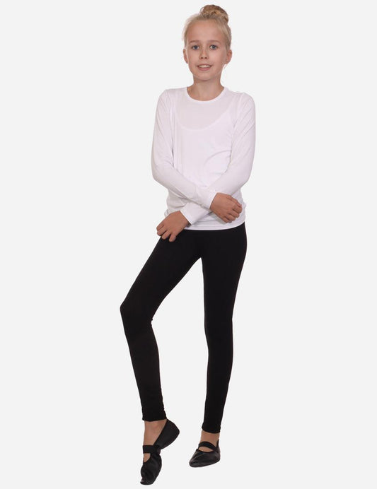 A girl in a white long-sleeved shirt and black elastics stands with her arms crossed.