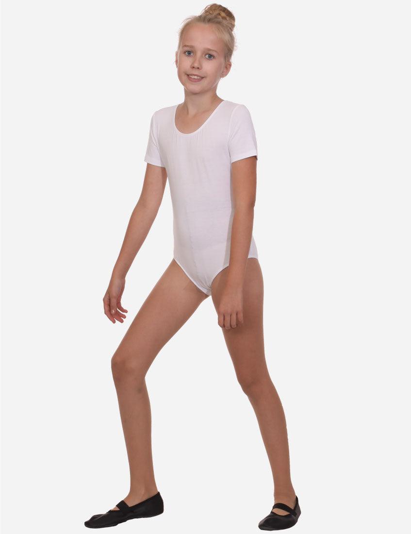 Confident young dancer in a white short sleeve leotard posing with one hand on her hip, wearing black ballet shoes.