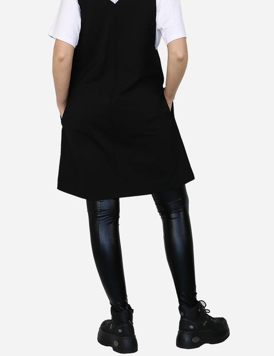 Back view of a woman in a sleek black faux leather leggings with a white shirt and black platform boots.