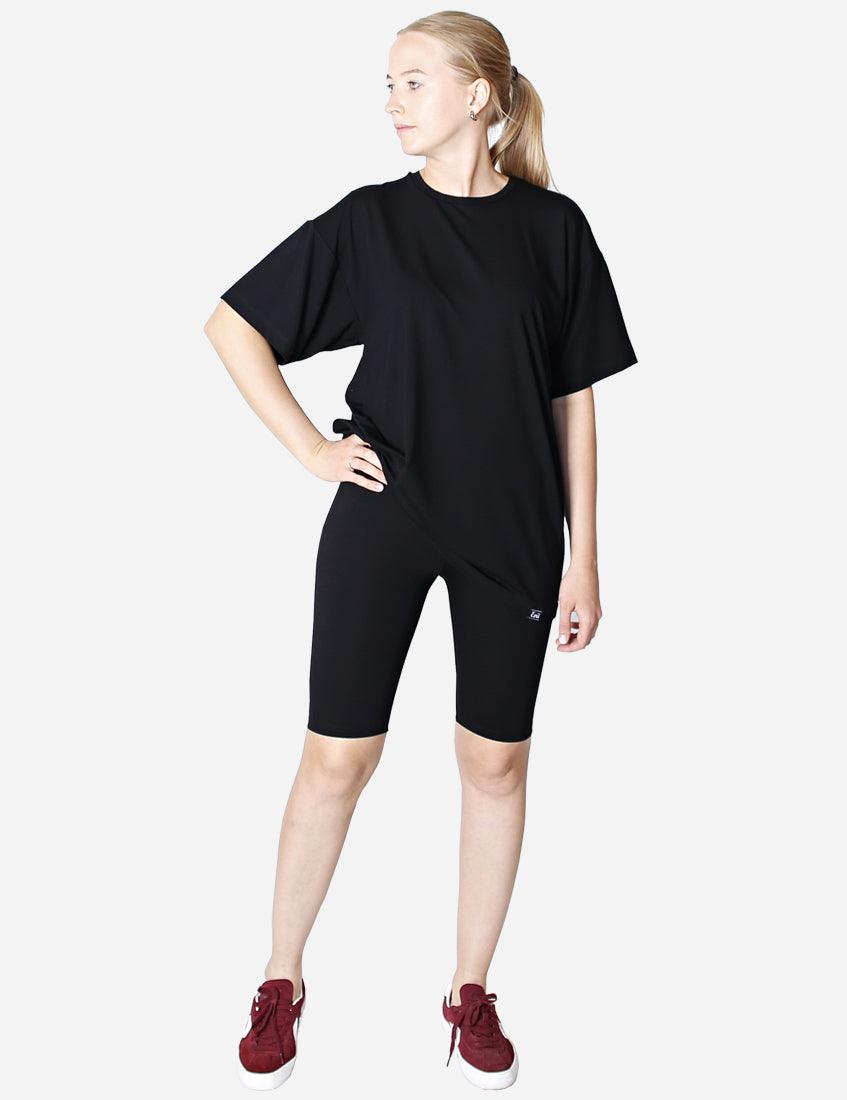 Back view of a woman wearing an oversized black unisex t-shirt on a white background